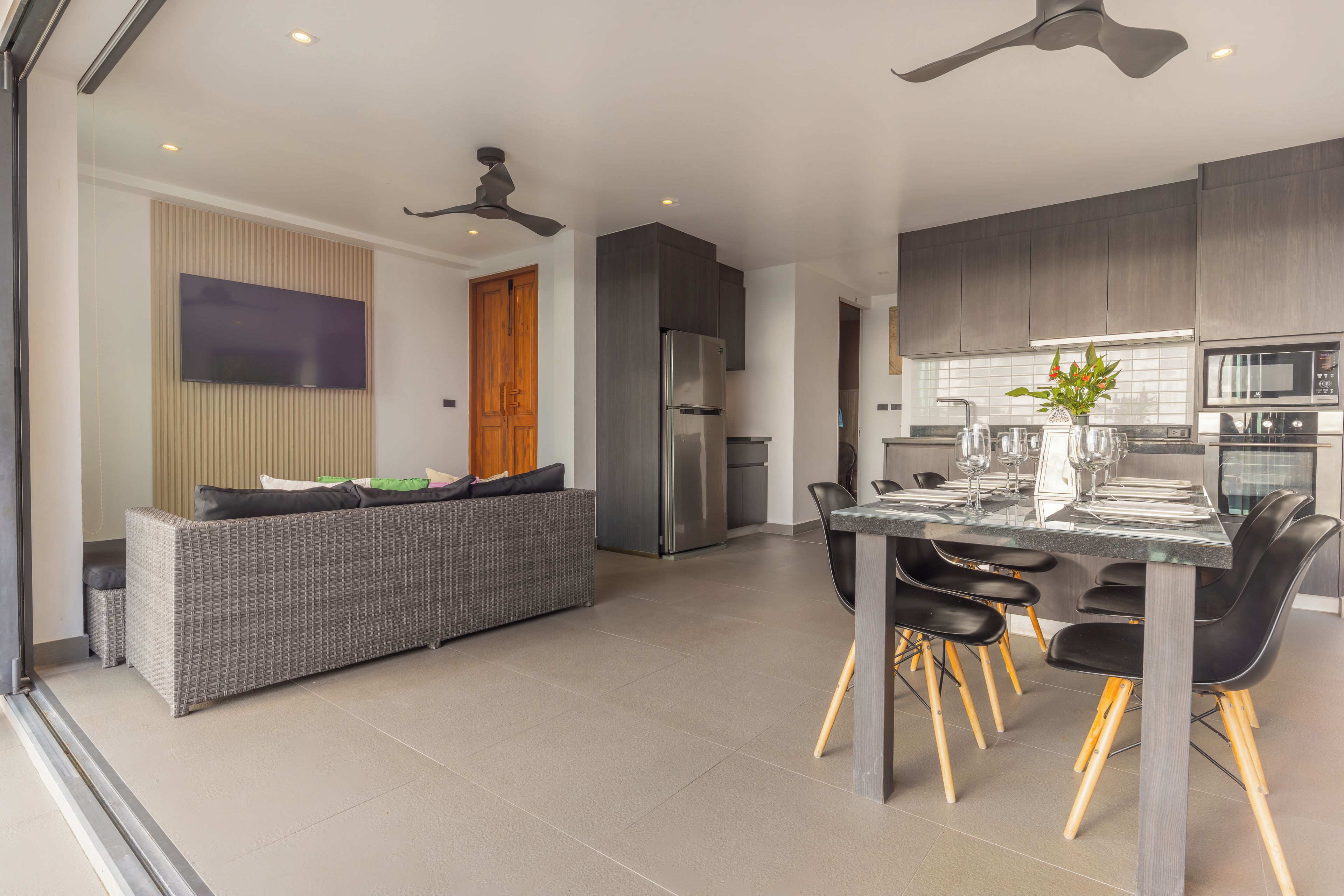 Una cocina moderna con comedor, que cuenta con horno empotrado, microondas y un televisor de pantalla plana grande montado en la pared.