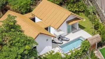 A modern house with a pool, surrounded by lush greenery.