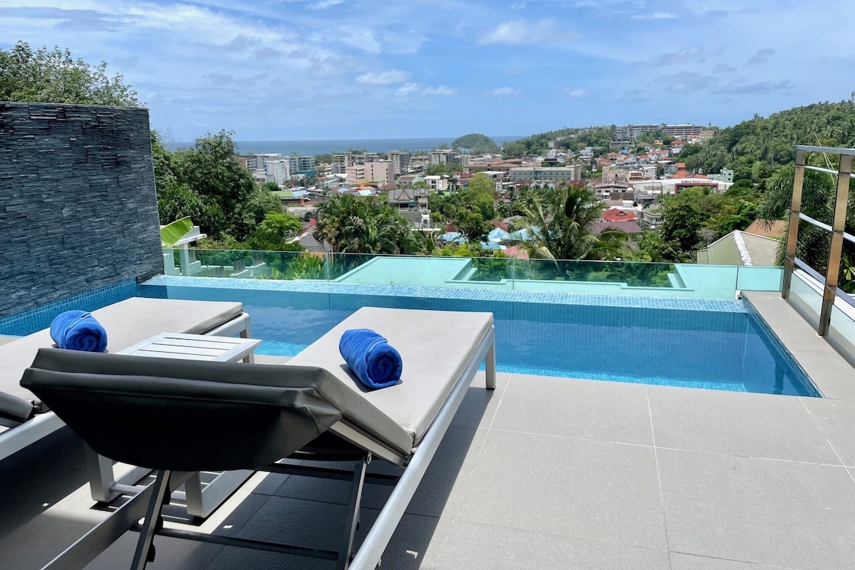 Une piscine à débordement située sur le toit, avec des chaises longues et un mur en pierre.