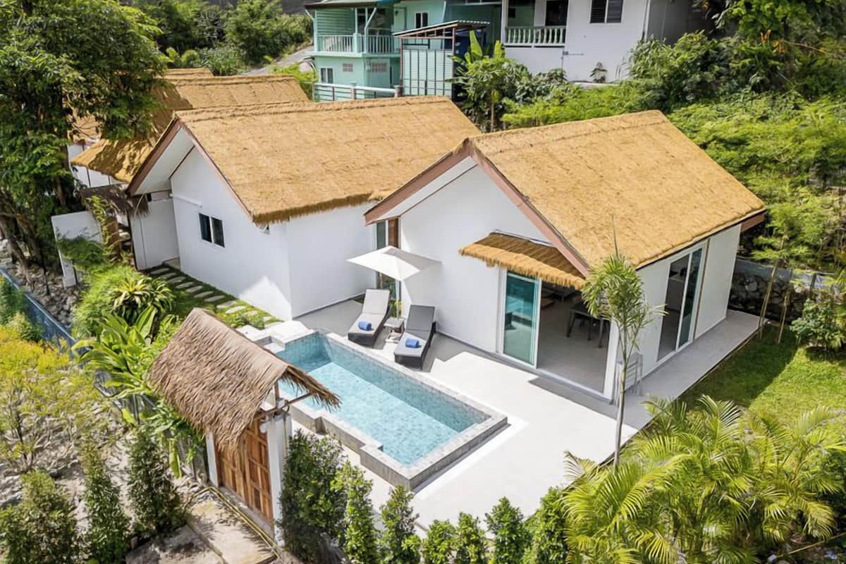 Una casa moderna con piscina, rodeada de exuberante vegetación.