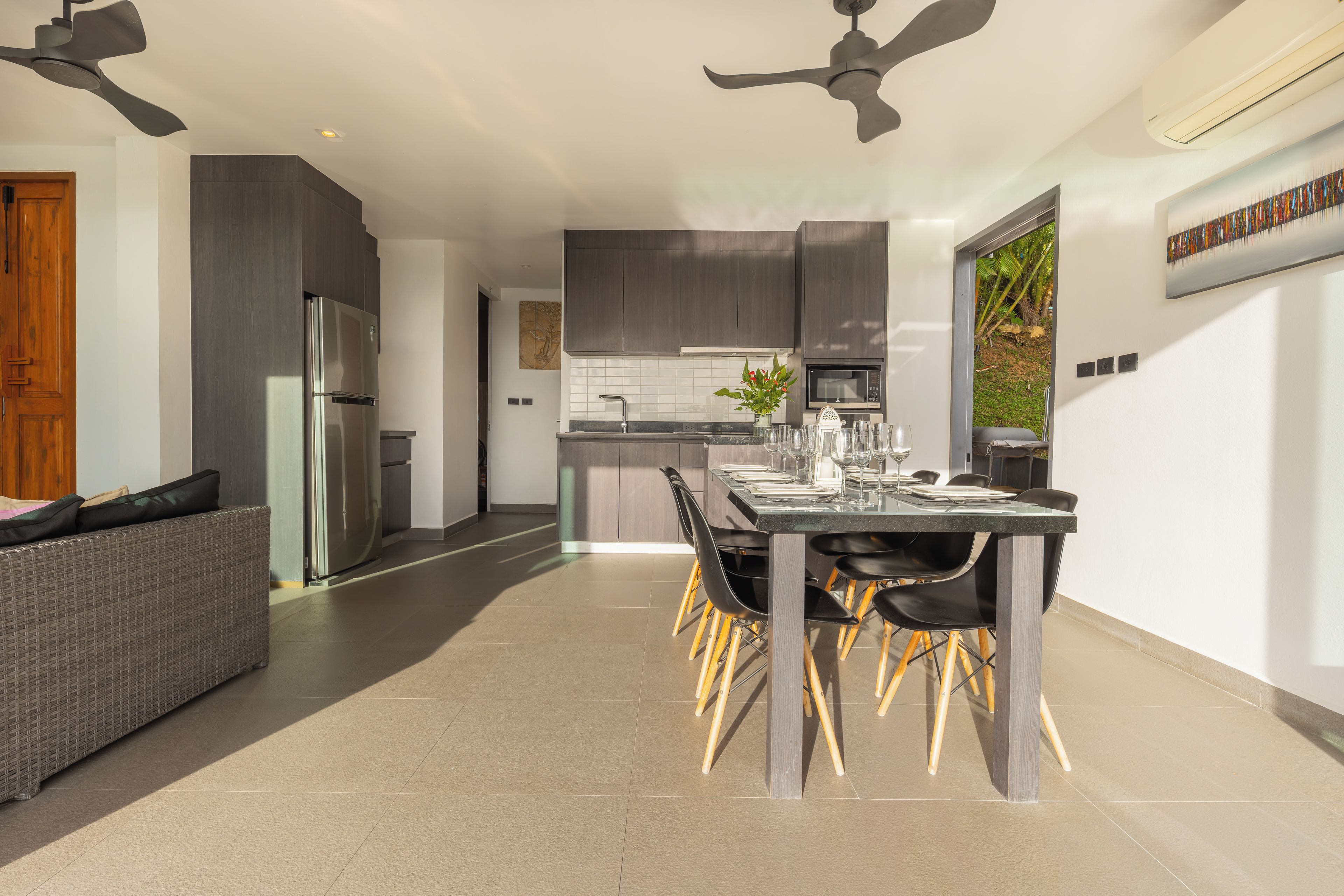 A modern kitchen with a dining area, featuring a stainless steel refrigerator, a microwave, and a dining table set for six.