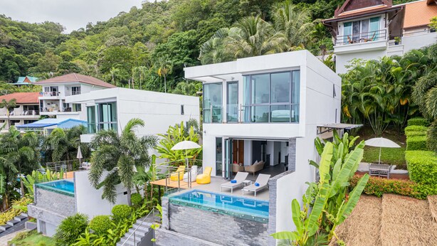 Ein modernes Haus mit Swimmingpool, Balkon und üppiger Bepflanzung.