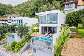 Une maison moderne dotée d’une piscine, d’un balcon et d’une végétation luxuriante.