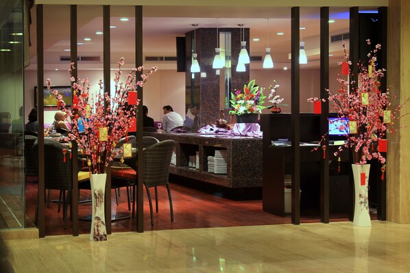 Un vestíbulo de hotel con una recepción, zona de estar y arreglos florales decorativos.