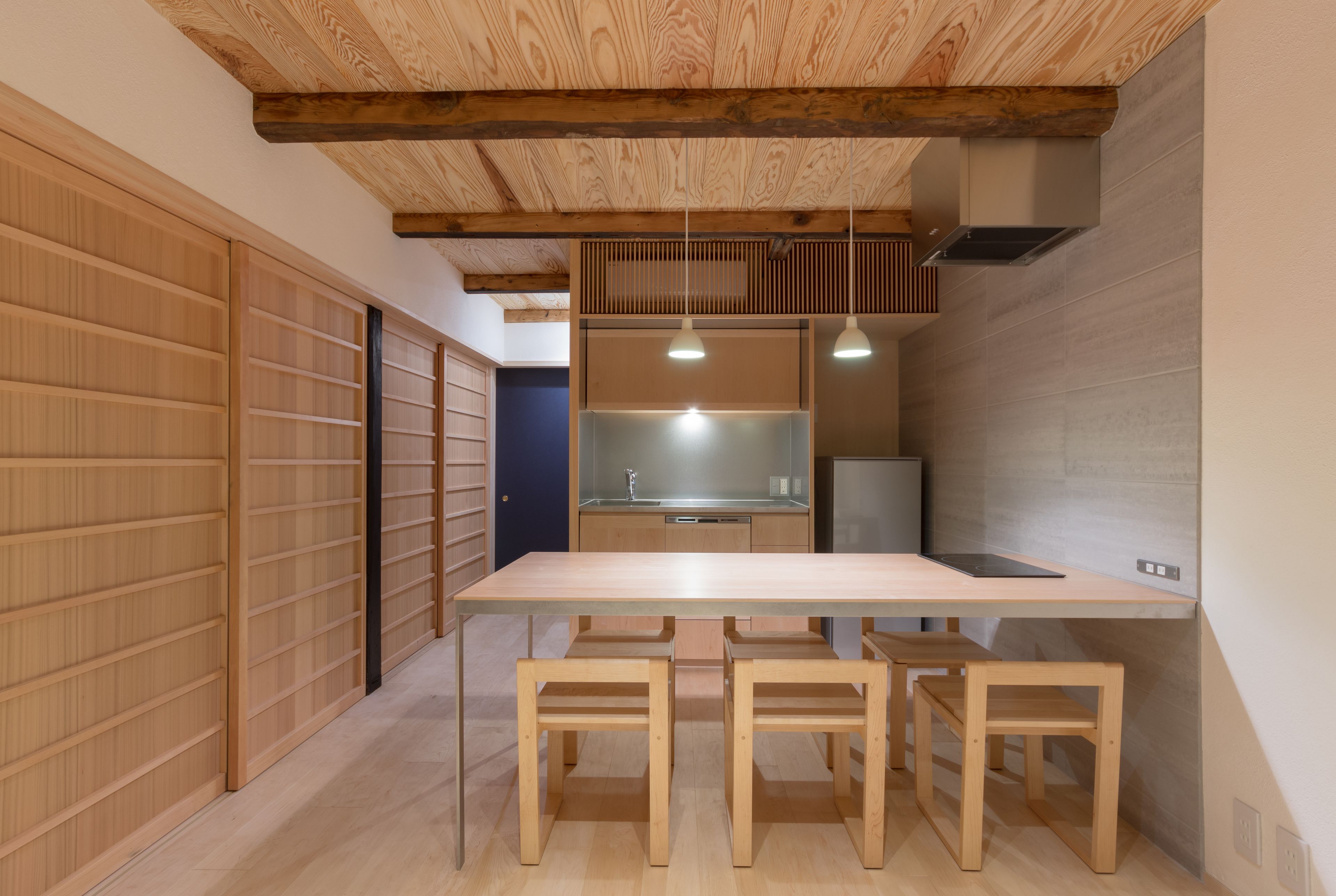 A modern kitchen with a wooden table and chairs, a built-in oven, and a large window.