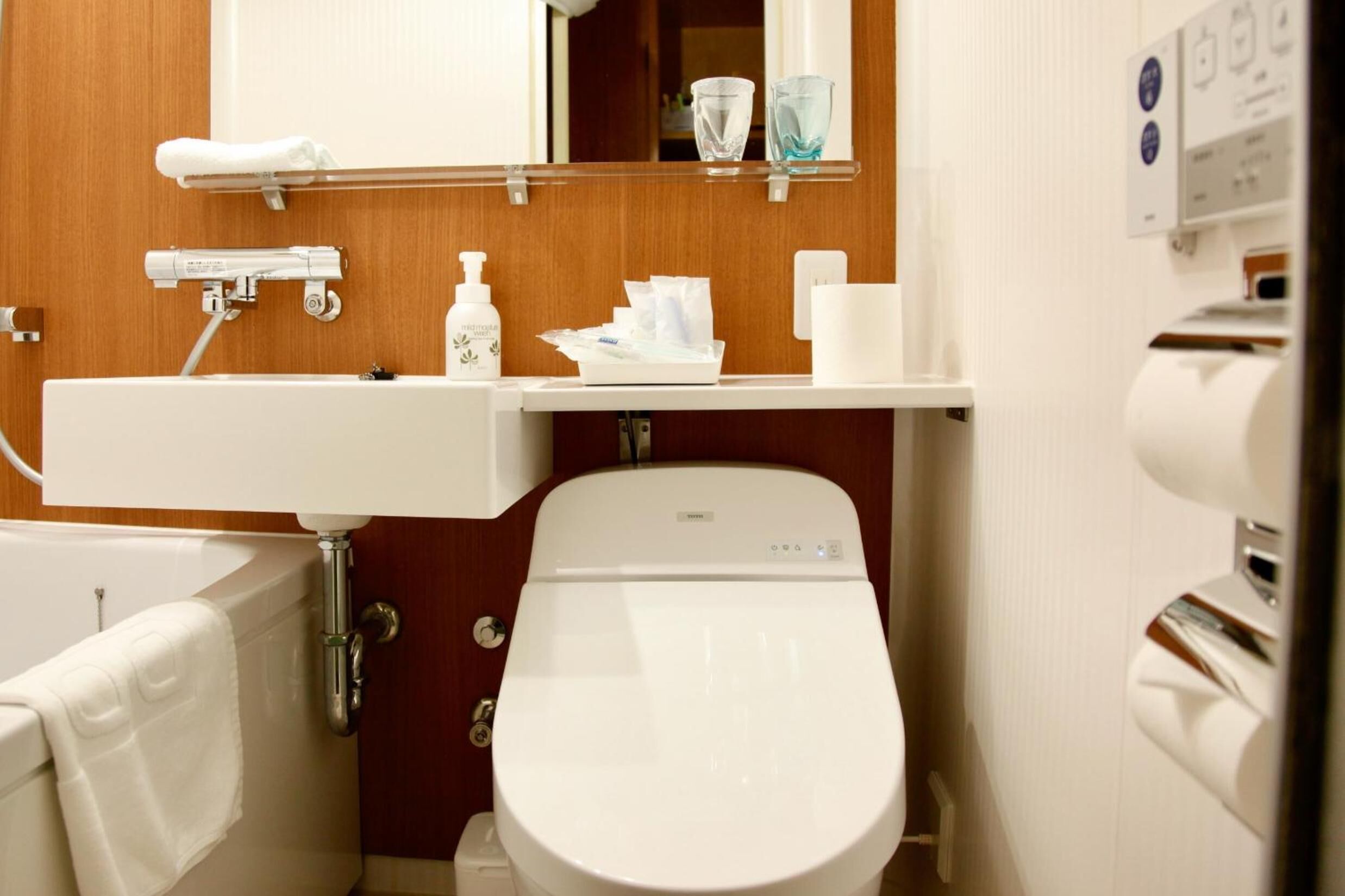 A bathroom with a white toilet, a sink, a mirror, and a towel rack.