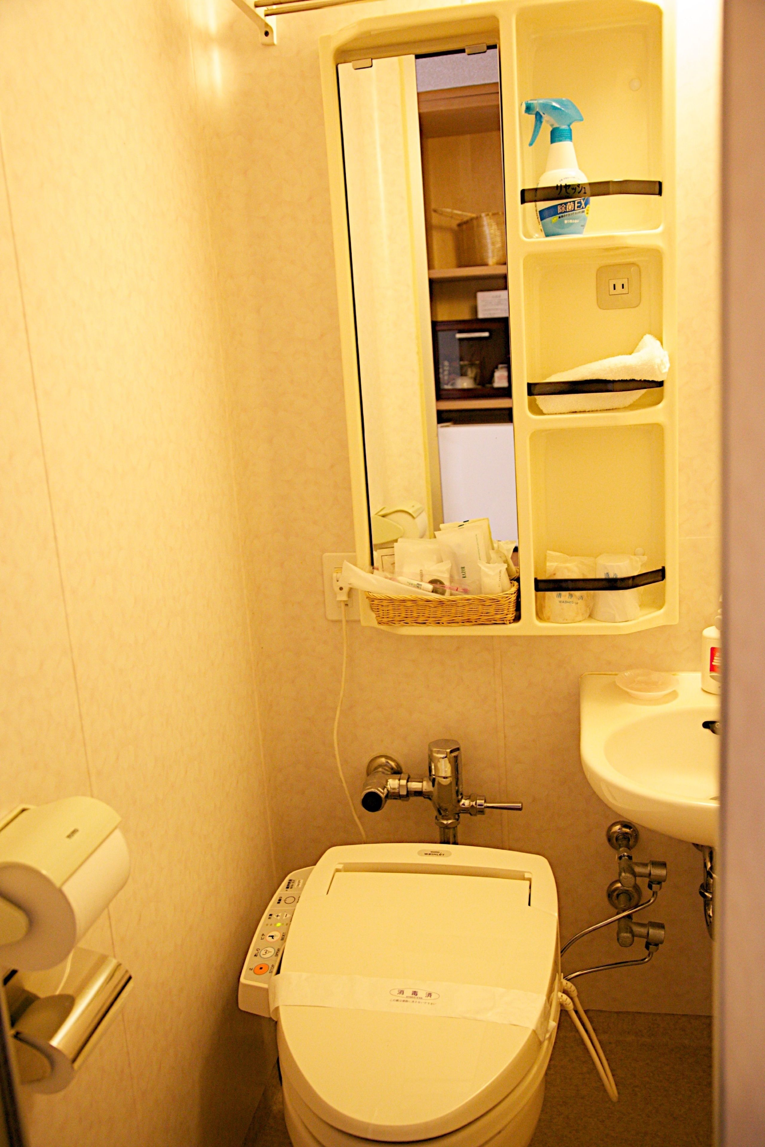 Un baño pequeño con inodoro, lavamanos y espejo.