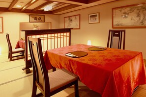 A traditional Japanese dining room with tatami flooring, a low table with a red tablecloth, and wooden chairs. - Karuizawa Tsuruya Ryokan (Karuizawa)