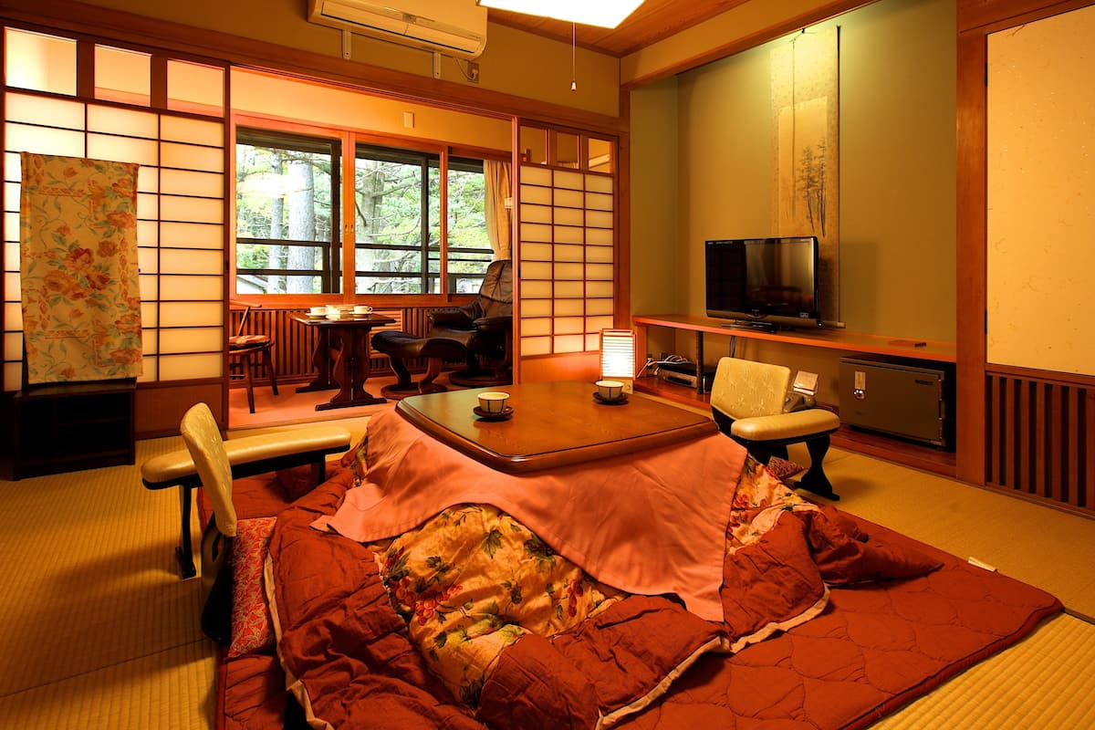 Une pièce de style japonais traditionnel, avec un sol recouvert de tatamis, une table basse et un téléviseur.