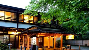 Een traditioneel Japans gebouw met een overdekte ingang, stenen lantaarns en een bord met Japanse karakters.