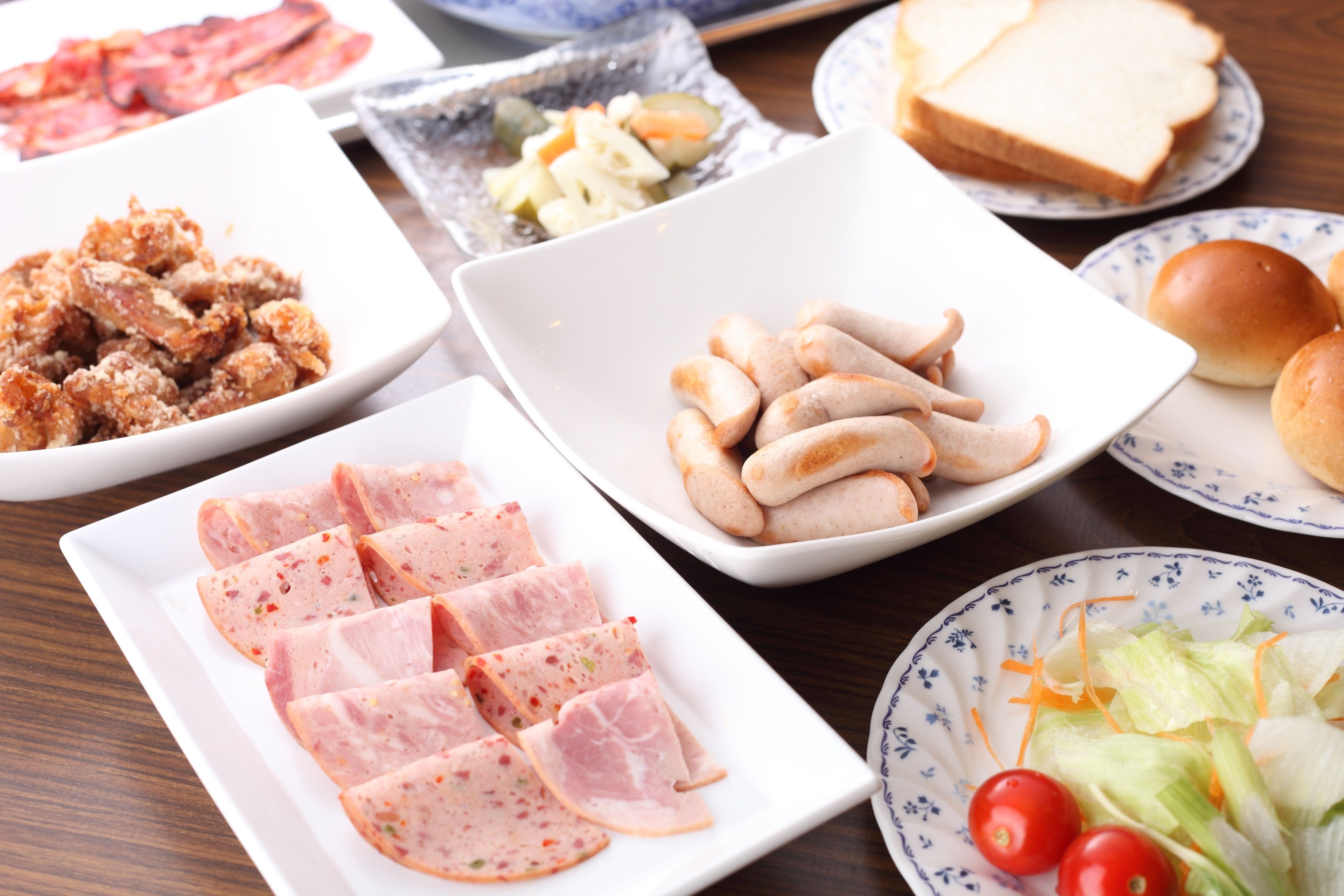 A table with various food items including sliced meat, bread, and vegetables.