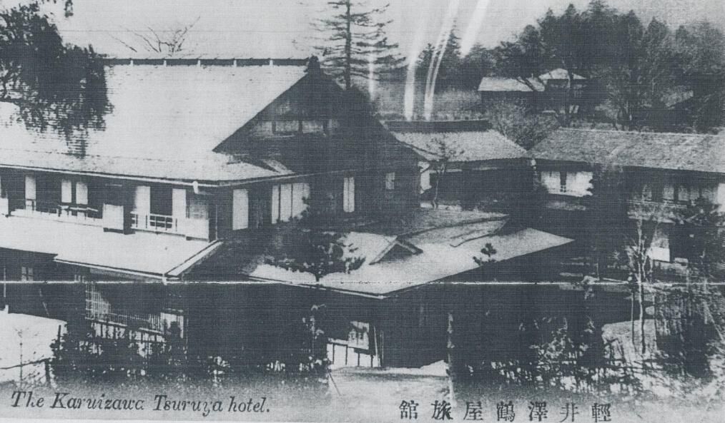 A historical building with a prominent central structure and smaller annexes. It features a symmetrical layout with a central tower-like building and additional wings. The architecture is traditional with a flat roof and wooden construction.