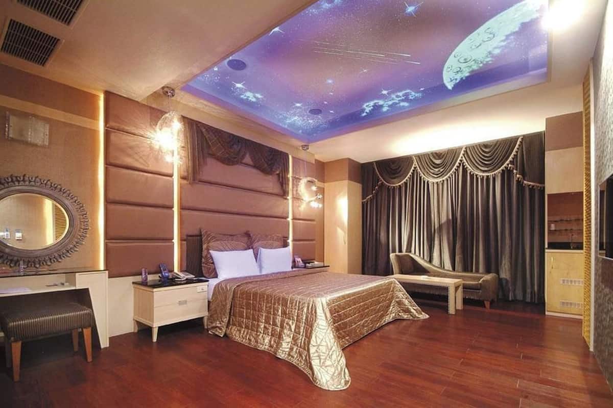 A bedroom with a bed, a desk, a chair, and a ceiling projection of space.