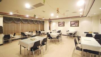 A conference room with multiple tables and chairs, arranged in rows.