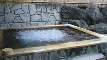 A stone wall with a wooden frame around a hot spring area.