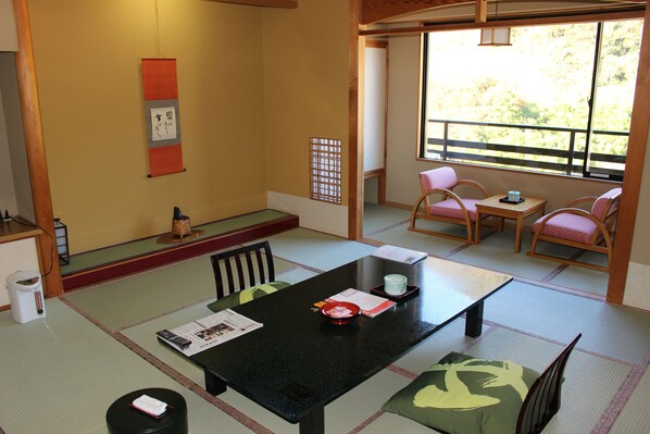 A traditional Japanese room with tatami flooring, a low table with a cushion, and a view of the outdoors through a sliding door. - Matsuriya Yuzaemon (Fukushima)