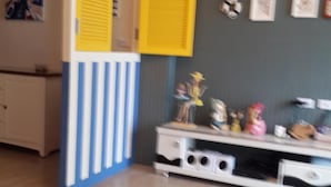 A room with a white cabinet, a blue and white striped partition, and a white entertainment unit with various items on top. - Aegean Sea Baoli (Taitung)