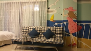 A room with a plaid sofa, a bed, and a mural of a seascape with a sailboat and a woman in a hat. - Aegean Sea Baoli (Taitung)