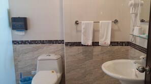 A bathroom with a toilet, sink, and a towel rack with two towels.