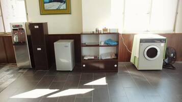 A laundry area with a washing machine, a small refrigerator, and a cabinet.