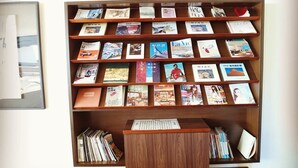 A bookshelf with various books and magazines, a small wooden table in front, and a framed picture on the wall. - Tea Cloud Guest House (Alishan)