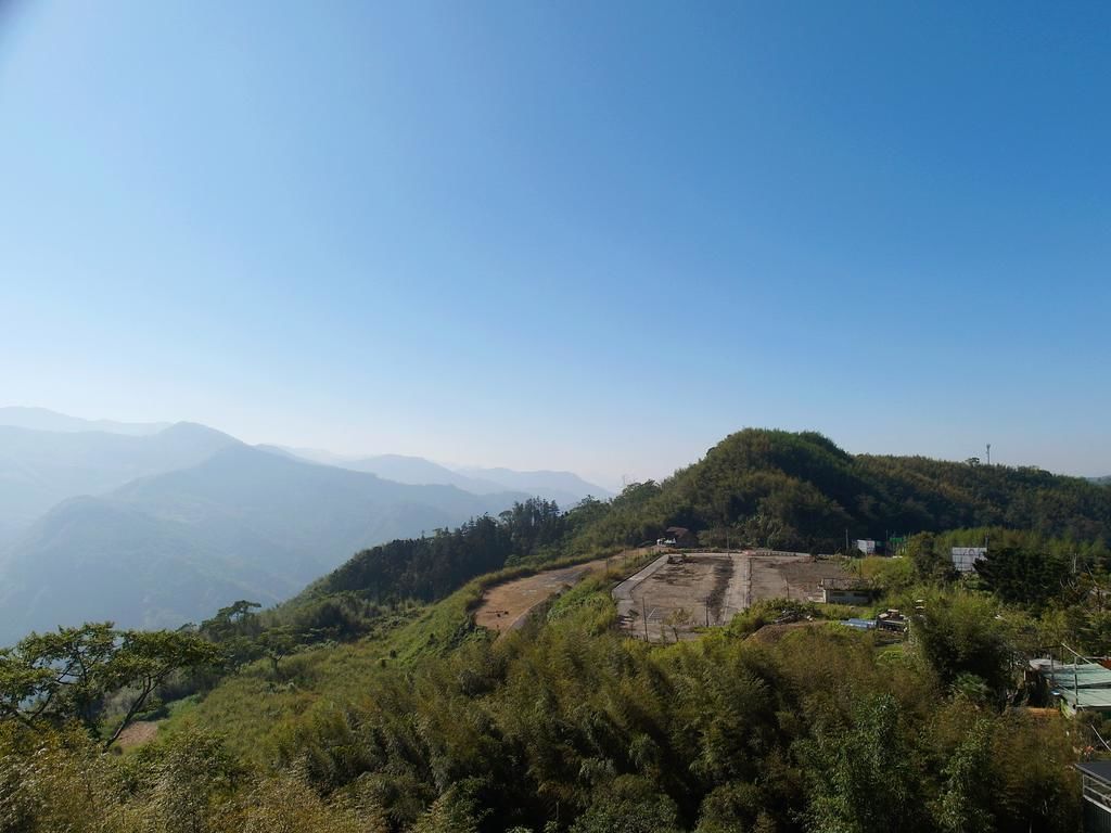 Paisagem acidentada com uma vasta área aberta que parece ser um canteiro de obras ou terreno desmatado.