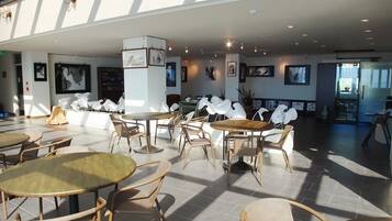 A spacious indoor area with multiple tables and chairs, featuring a modern design with natural light from skylights.