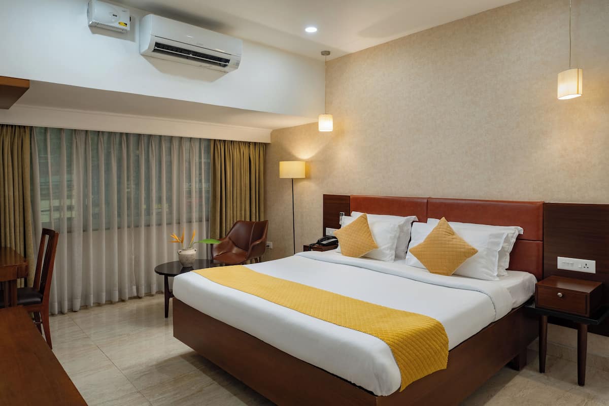 Habitación de hotel con una cama grande, un escritorio, una silla y una ventana con cortinas.