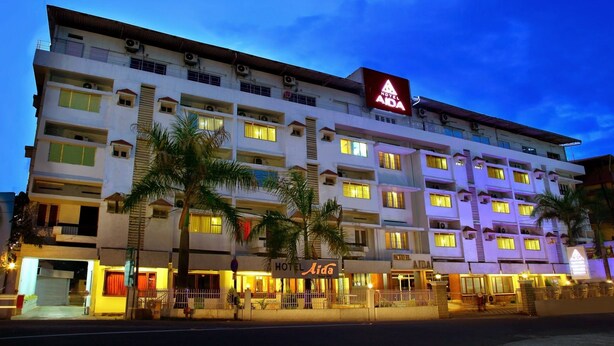 A multi-story hotel with a prominent ADA sign, multiple balconies, and a well-lit entrance. - Hotel Aida (Kottayam)