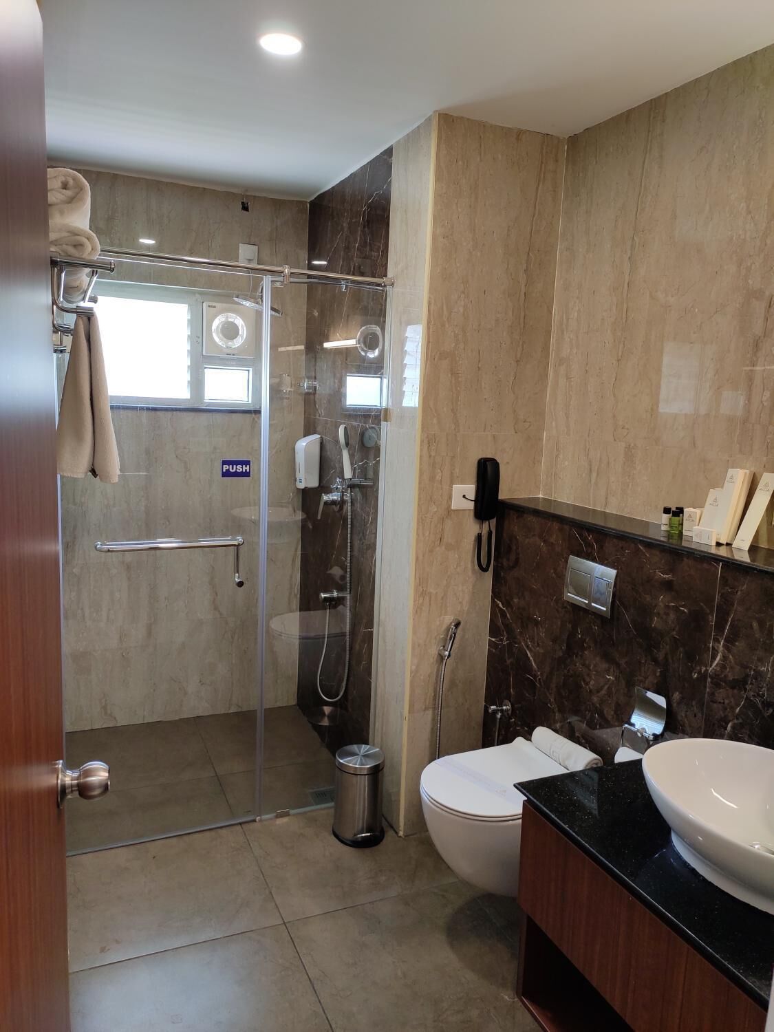 A modern bathroom with a glass-enclosed shower, a toilet, and a sink.