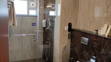 A modern bathroom with a glass-enclosed shower, a toilet, and a sink.