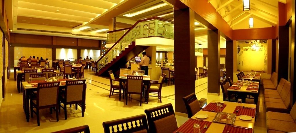 A spacious restaurant with multiple dining areas, a staircase, and a bar.