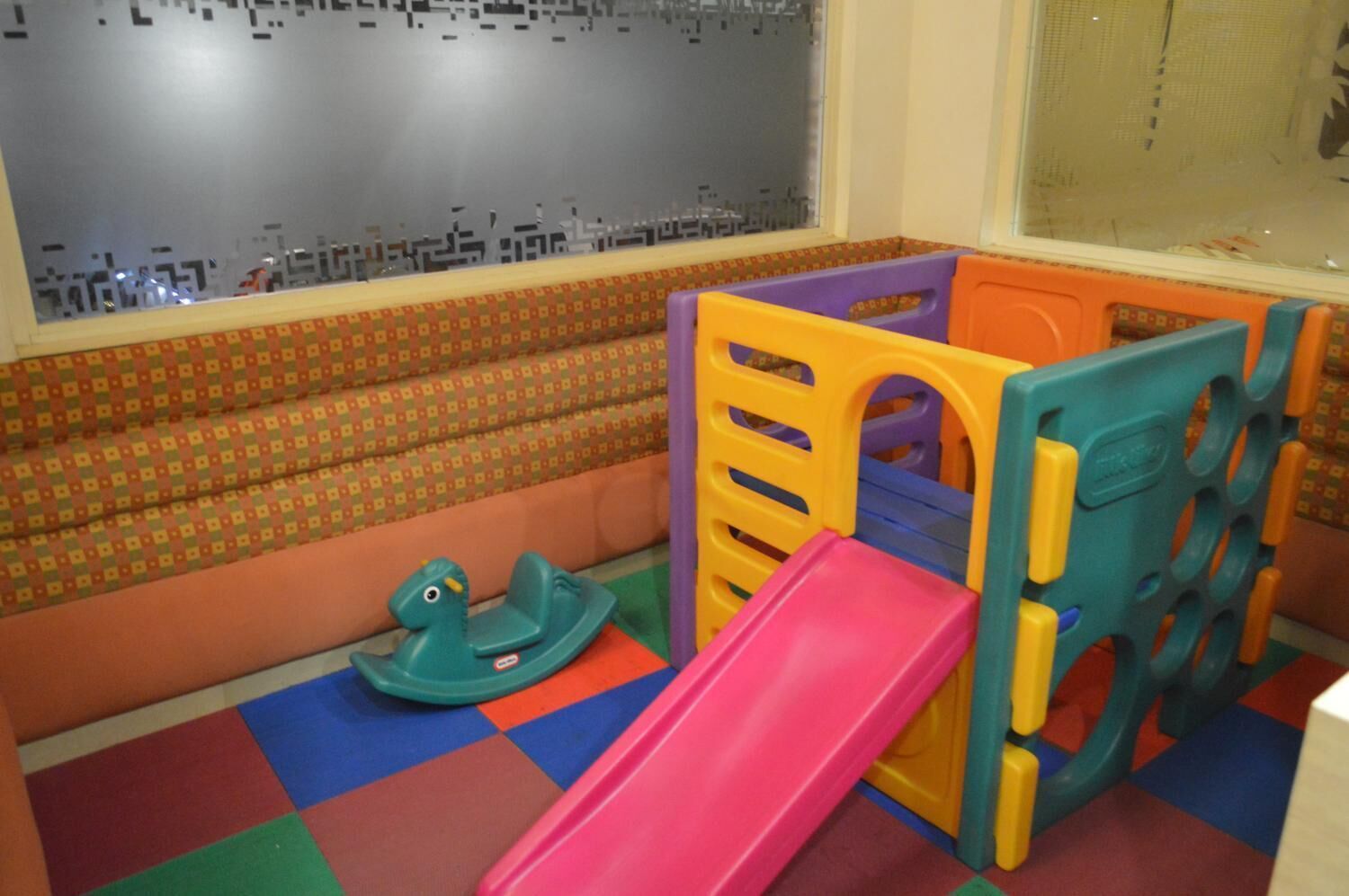 A children's play area with a colorful slide, a small rocking horse, and a playpen.