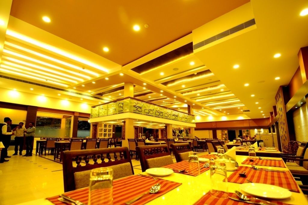 Een ruim restaurant met hoge plafonds en moderne verlichting. Tafels staan netjes gedekt.