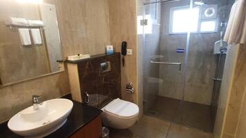 A modern bathroom with a double sink, a toilet, and a glass-enclosed shower.