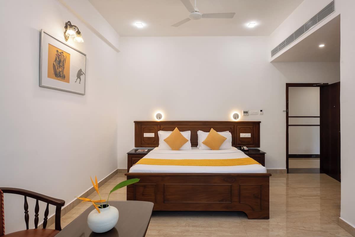 Un dormitorio con una cama de madera, mesitas de noche, una silla y una lámpara fijada en la pared.