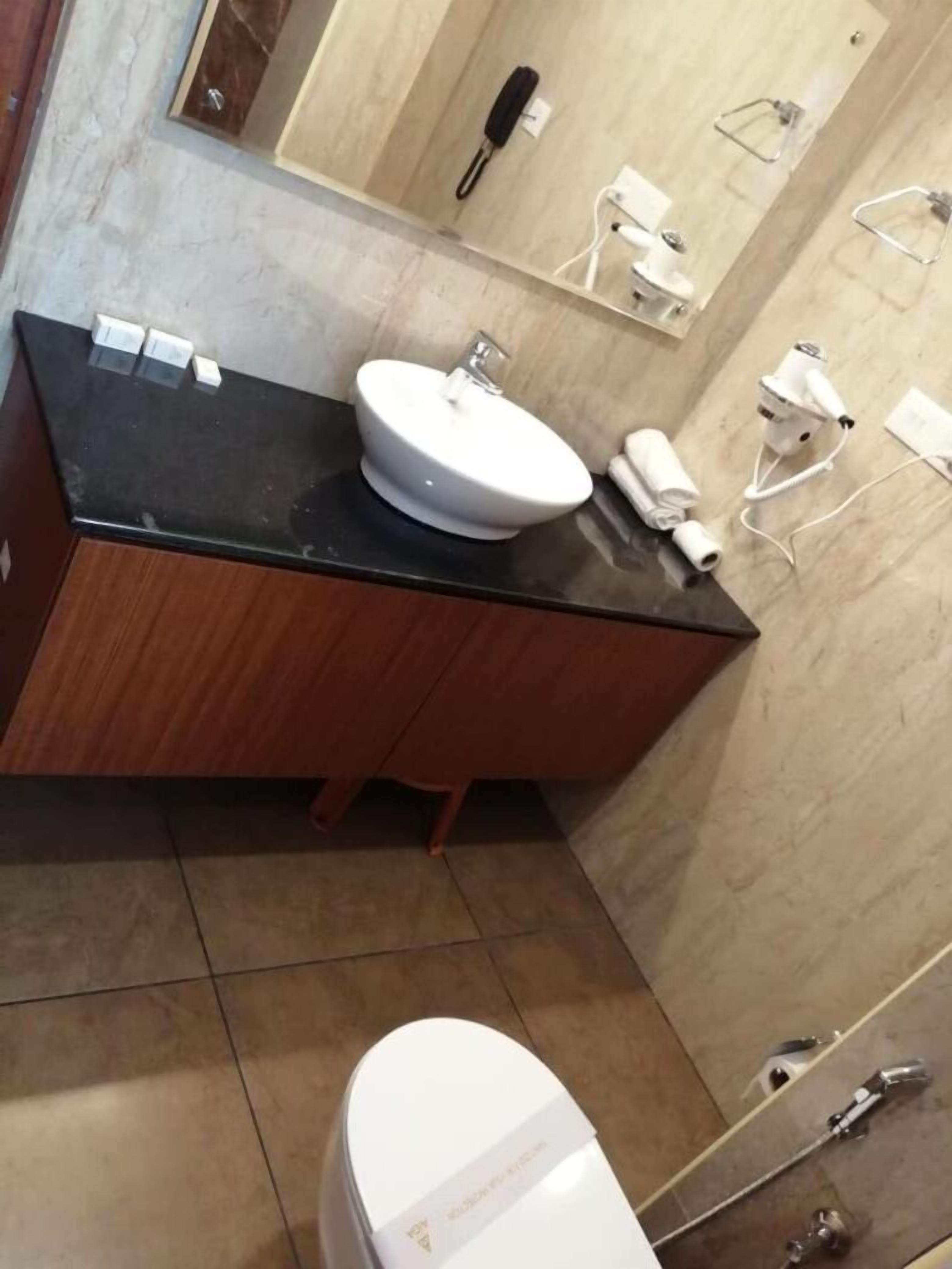 A modern bathroom with a black countertop, a white sink, and a toilet.