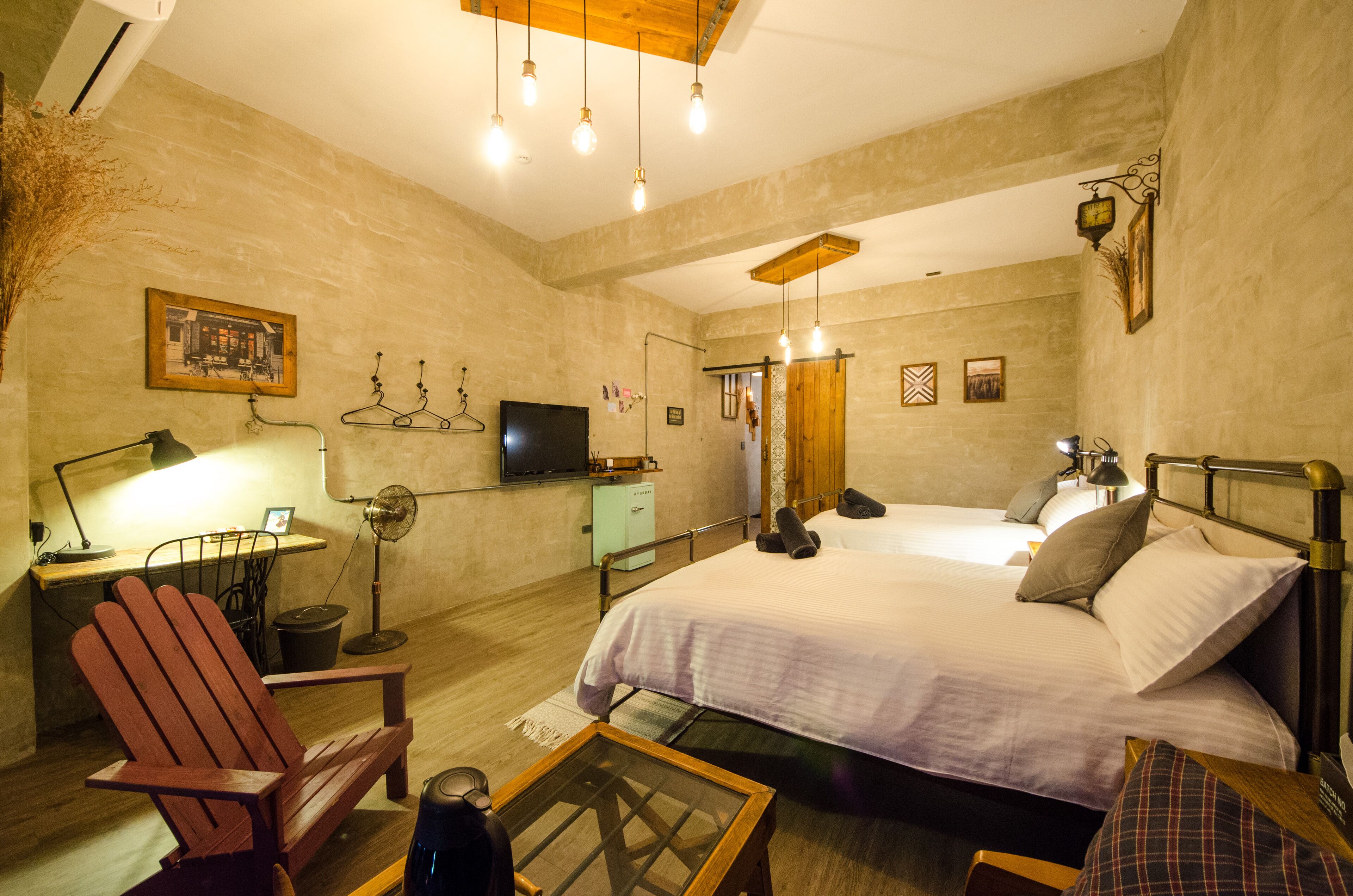 Un dormitorio acogedor con cama, una silla de madera, una mesita y un televisor sobre un mueble.