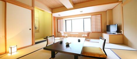 A traditional Japanese room with tatami flooring, a low table, and a television on a stand.