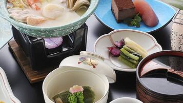 A variety of Japanese dishes including sushi, sashimi, and a hot pot, arranged on a table with traditional Japanese ceramics.