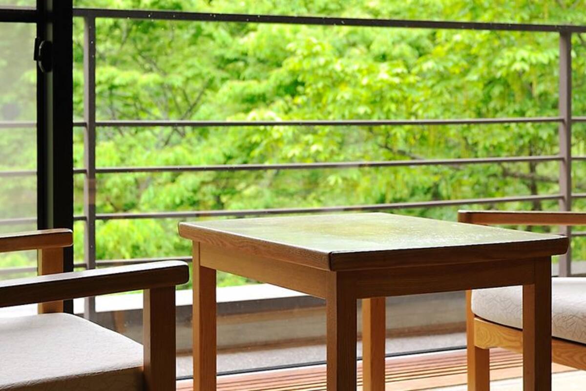 Una habitación con un ventanal grande, una mesa de madera y dos sillas.