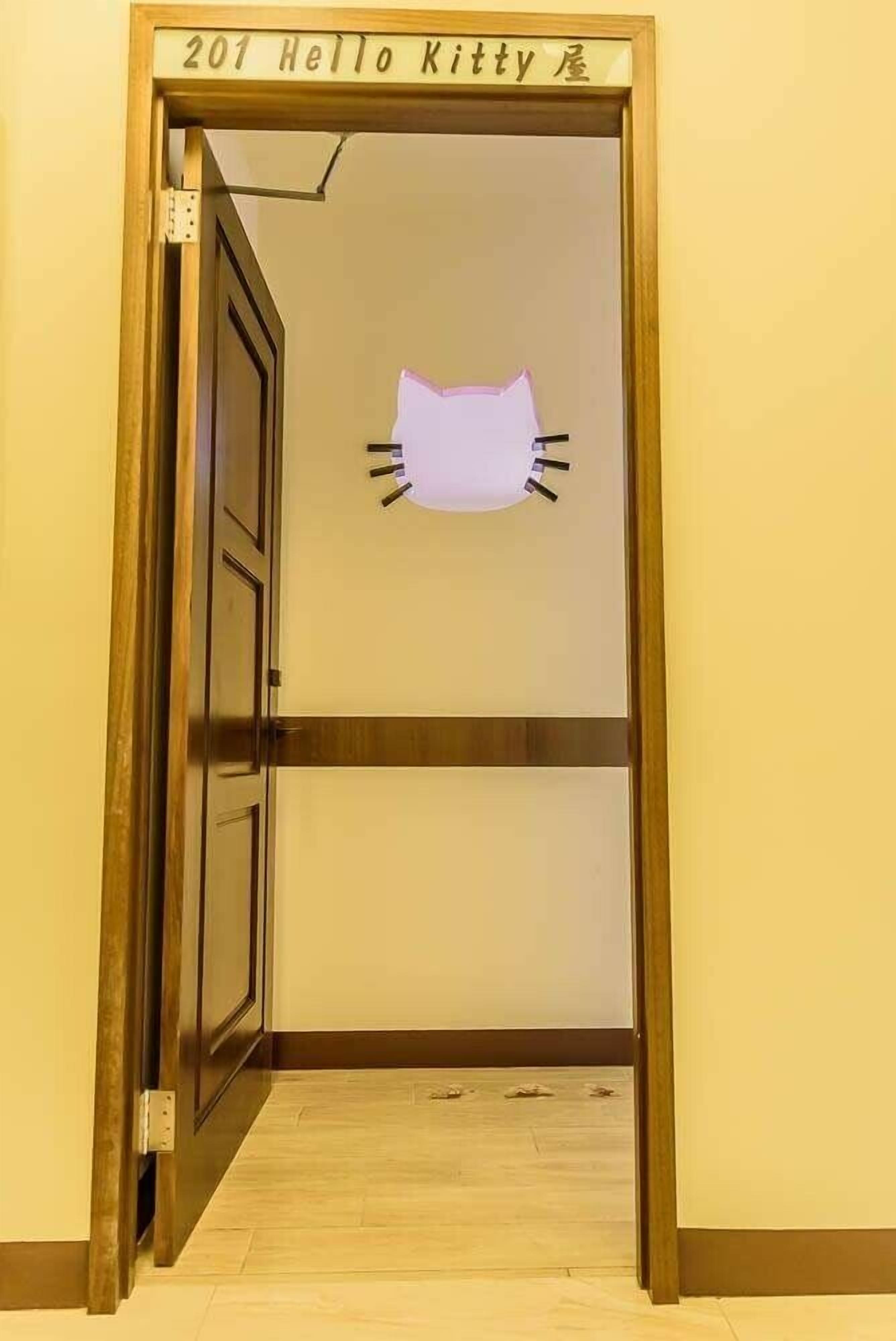 A room with a door labeled "201 Hello Kitty" and a cat-shaped decoration on the wall.