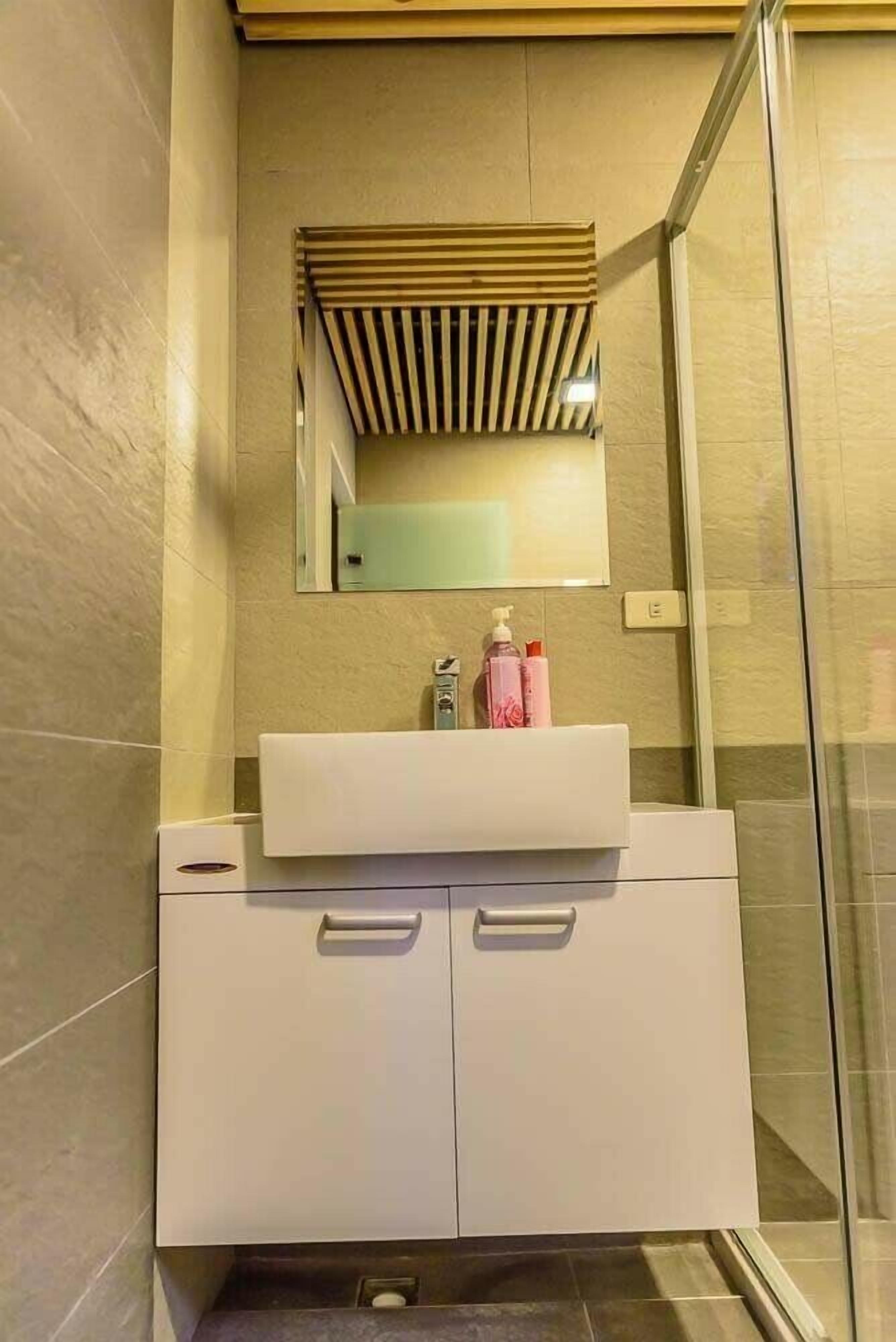 Ein modernes Badezimmer mit einem weißen Waschtisch, einem Spiegel und einer Duschkabine.