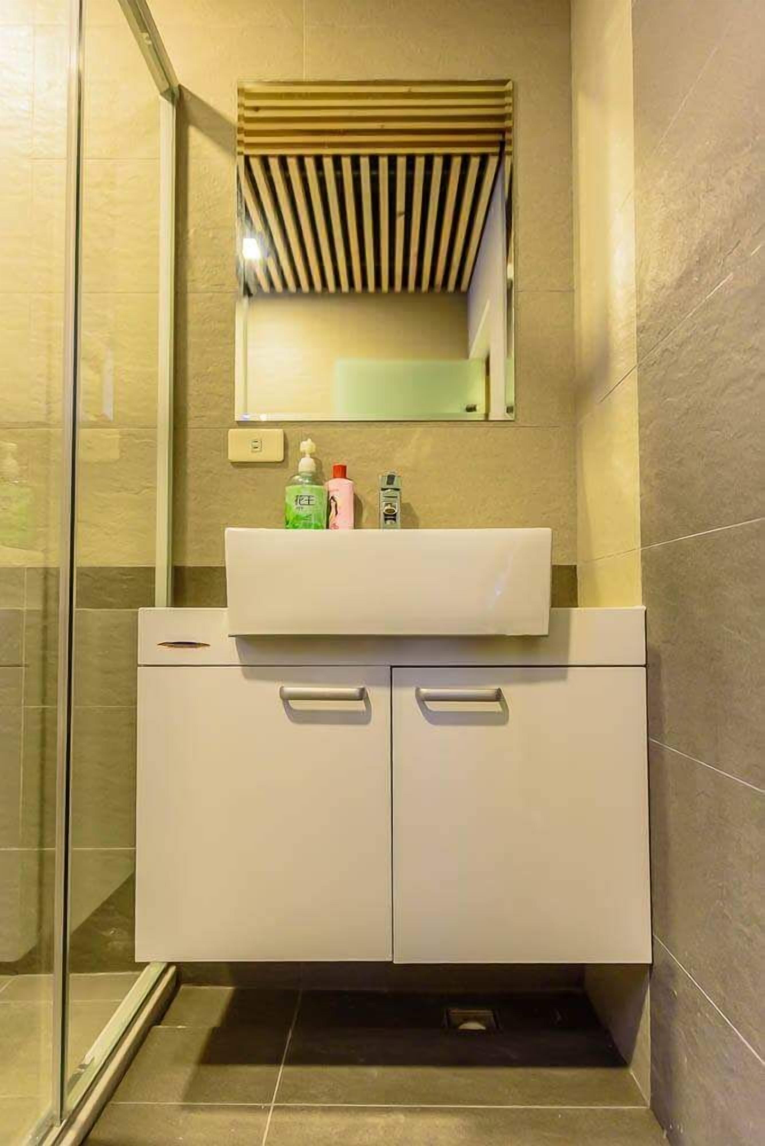 A modern bathroom with a white vanity, a mirror, and a shower area.