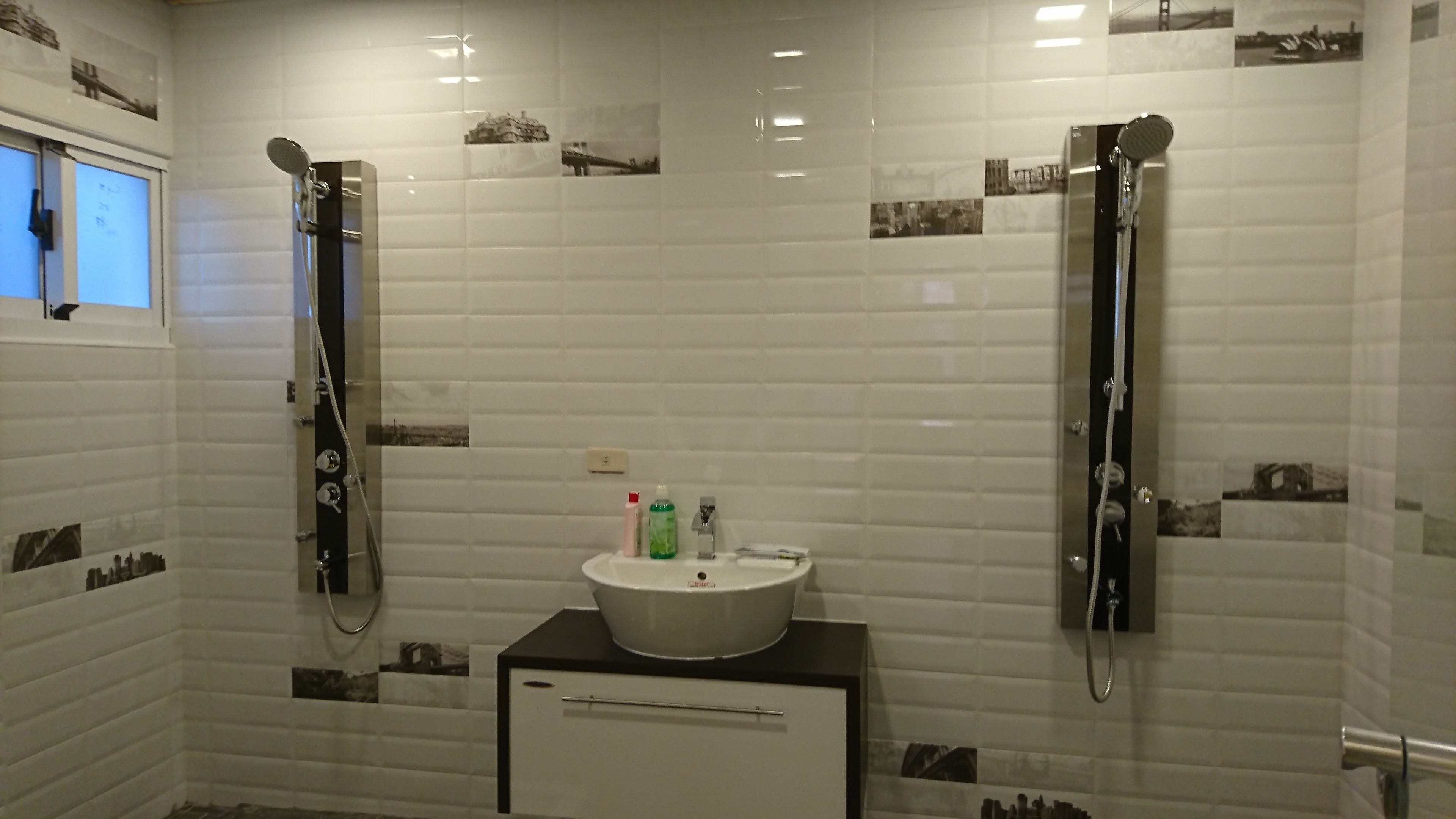 A bathroom with two showers, a sink, and a cabinet.