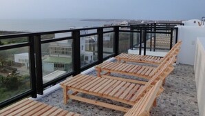 Une terrasse sur le toit, dotée de chaises longues en bois et offrant une vue sur la mer.