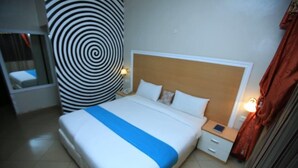 Ein Hotelzimmer mit einem großen Bett, einem Nachttisch, einer Wanduhr und einer runden Wanddekoration.