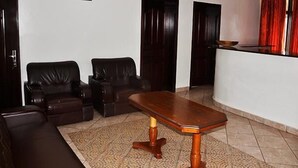 Ein Wohnzimmer mit einem dunkelbraunen Ledersofa, einem Holztisch und einem gemusterten Teppich.
