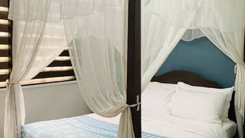 A four-poster bed with white net curtains, a blue patterned bedspread, and white pillows.