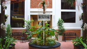 A courtyard with a sign reading "PARADORES DE VIGAN A PLACE IN TIME," surrounded by potted plants and two black metal chairs. - Paradores de Vigan (Vigan)